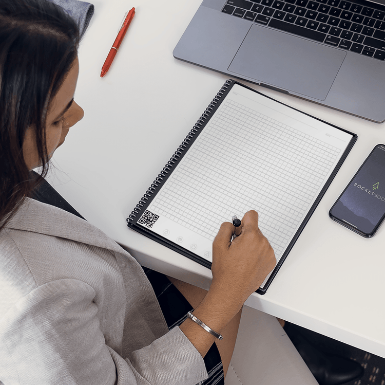woman writing on Rocketbook Matrix graph paper page